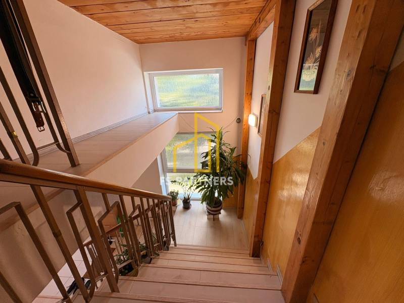 Ein Flur mit Treppe, Holzvertäfelung und Blumen in einem Einfamilienhaus.