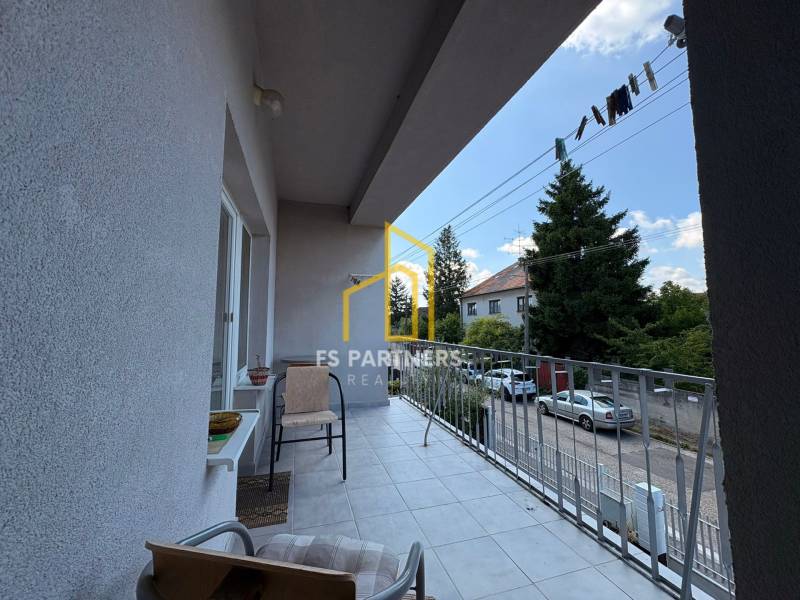 Der Balkon eines Einfamilienhauses in Komárno mit Blick auf die Straße mit parkenden Autos und Bäumen.