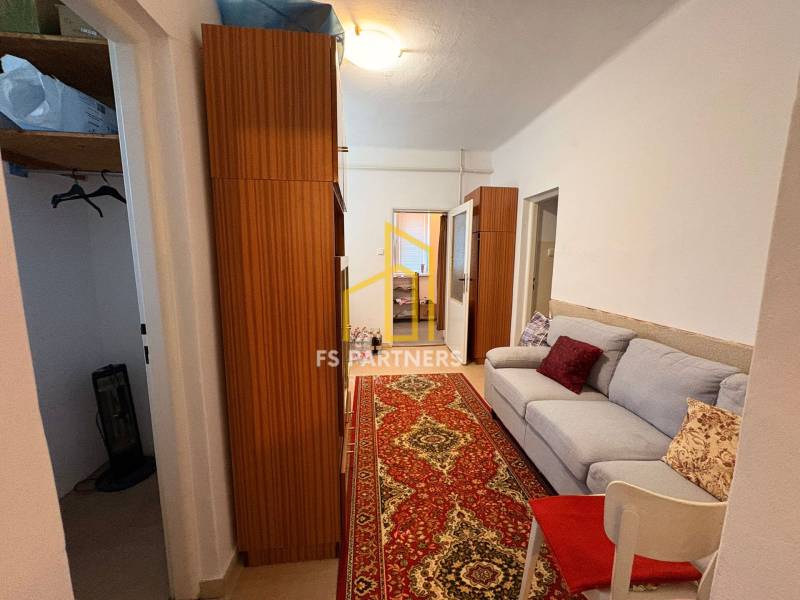 Ein Flur in einem Einfamilienhaus mit einem Sofa, einem Holzschrank und einem roten Teppich.