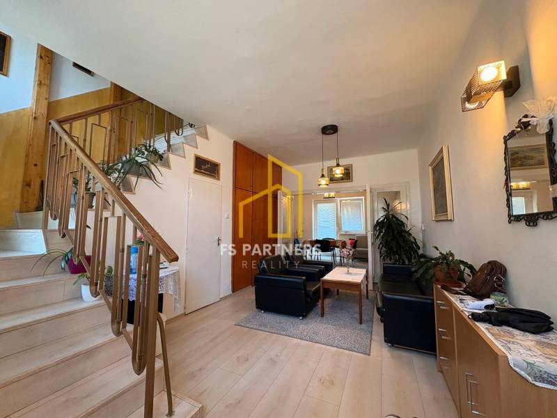 Wohnzimmer mit Treppe in einem Einfamilienhaus, mit Sitzgelegenheit und dekorativen Elementen.