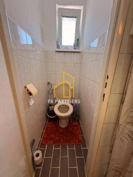 Badezimmer eines Einfamilienhauses mit Toilette, Fliesen und kleinem Fenster.