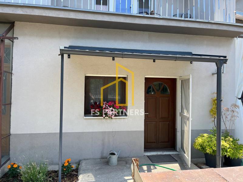 Ein Einfamilienhaus in Komárno mit einer Terrasse und Blumen vor dem Eingang.