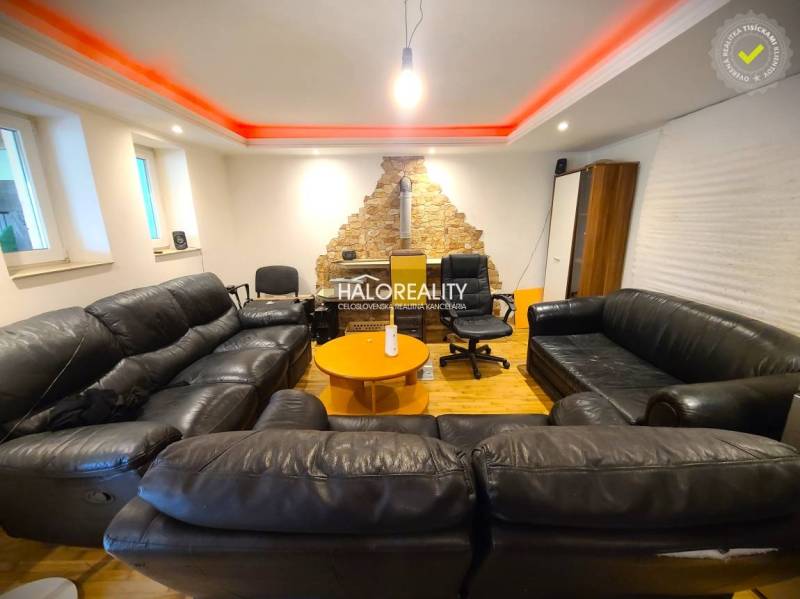 Wohnzimmer in einem Einfamilienhaus mit schwarzen Sofas und einer Steinwand.