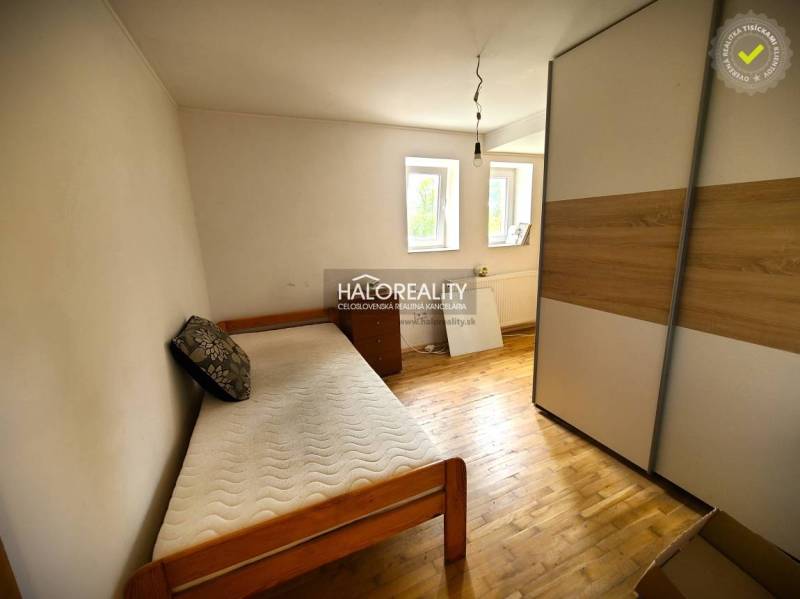 Ein Zimmer mit einem Einzelbett, einem Schrank und zwei Fenstern in einem Einfamilienhaus.