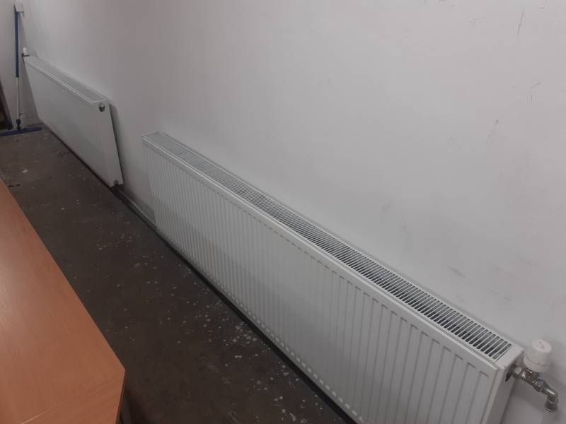 Heizkörper, die im Lager und in der Halle an der Wand mit Betonboden platziert sind.