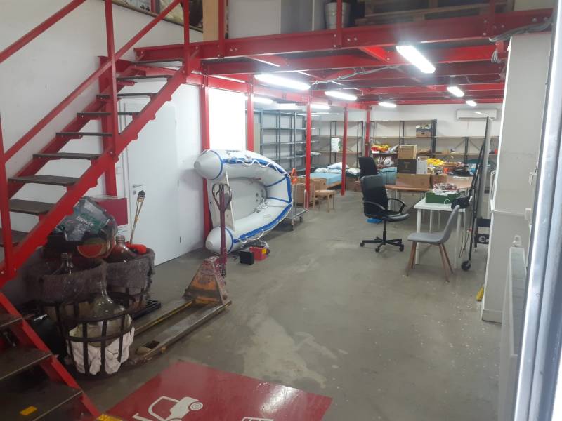 Lagerhallen und Lagerhäuser mit roter Treppe und Schlauchboot, verstreute Regale und Möbel.