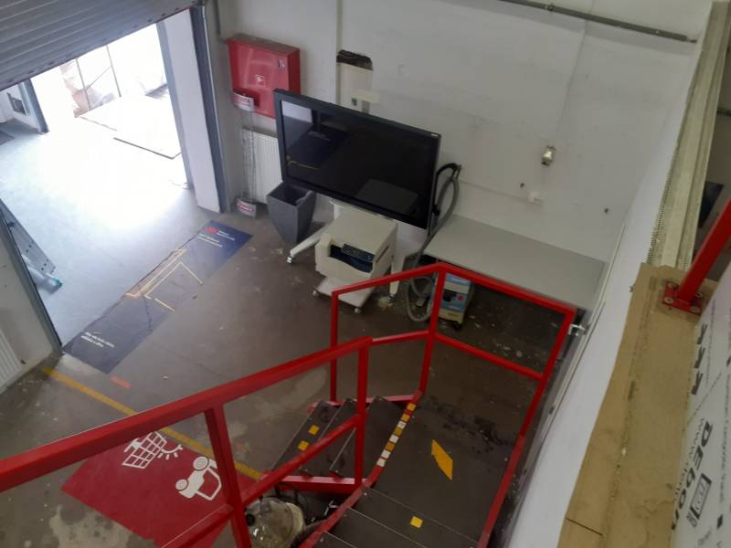 In Lagern und Hallen gibt es eine rote Treppe, einen Bildschirm und einen offenen Eingangsbereich.