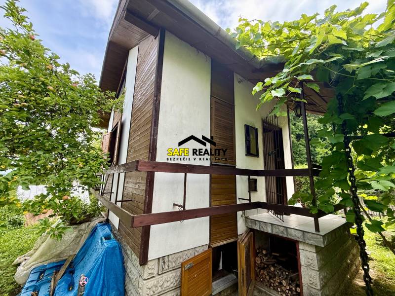Ein Ferienhaus in Mojša mit Holzelementen, umgeben von Grün und Bäumen.
