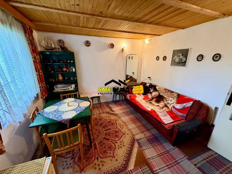 Wohnzimmer in einer Hütte mit Holzdecke, gemusterten Teppichen und bequemen Sitzgelegenheiten.