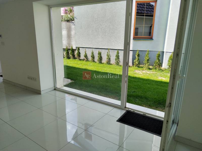 Innenraum eines Einfamilienhauses, weißer Boden, großes Fenster mit Blick auf den Garten.