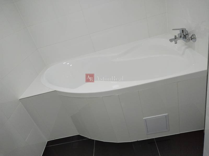 Weiße Badewanne mit Armatur im Badezimmer eines Einfamilienhauses.