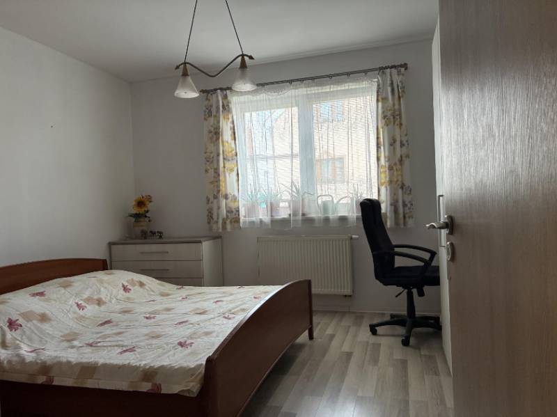 Schlafzimmer mit Bett, Arbeitsstuhl und Kommode in einem Einfamilienhaus.