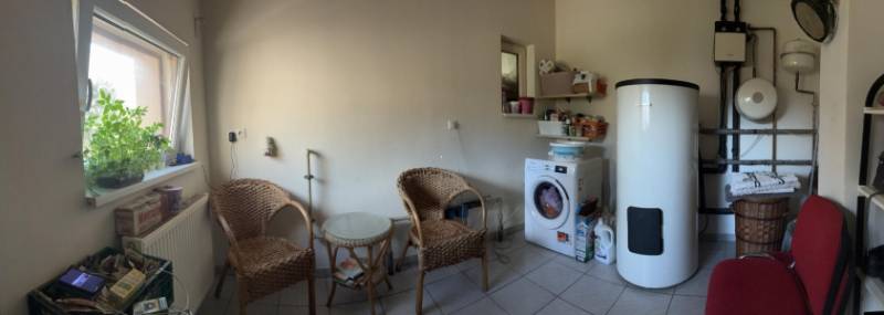 Waschküche in einem Einfamilienhaus mit Waschmaschine, Kessel und Holzmöbeln.