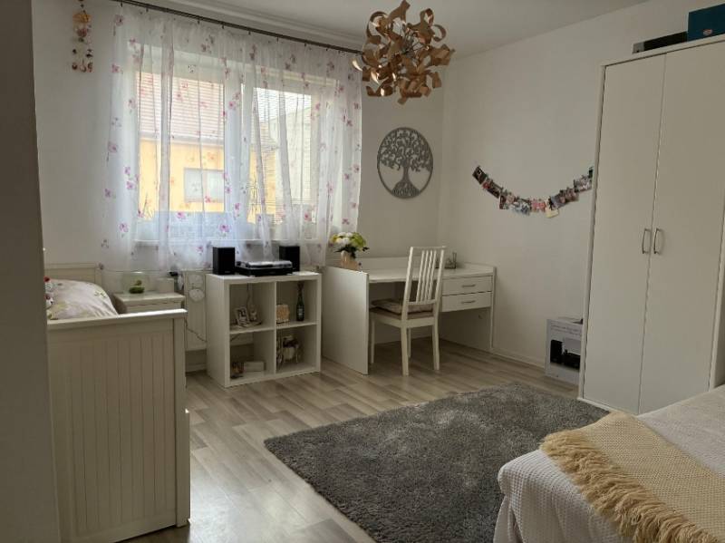 Helles Zimmer in einem Einfamilienhaus mit weißen Möbeln, Schreibtisch und Dekorationen.