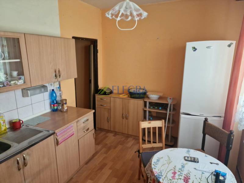 Küche in einer Einzimmerwohnung mit Holzschränken, Tisch und Kühlschrank.