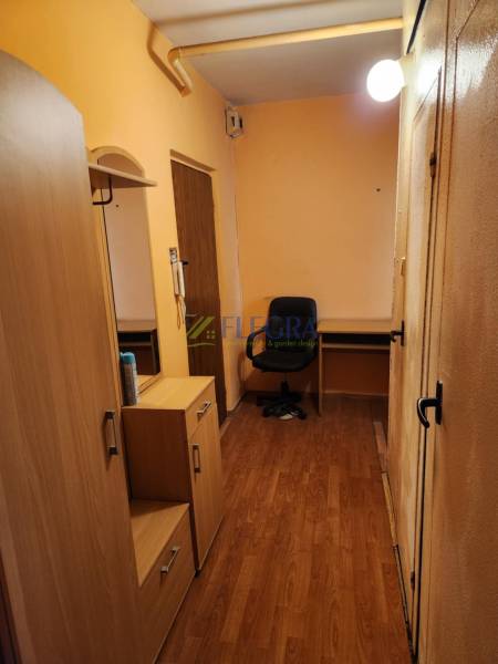 Ein enger Flur in einer Einzimmerwohnung mit Holzmöbeln und einem Stuhl.