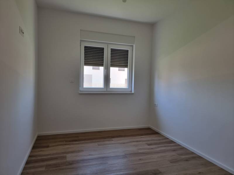 Ein Zimmer einer 4-Zimmer-Wohnung mit Holzboden, weißen Wänden und einem Fenster.
