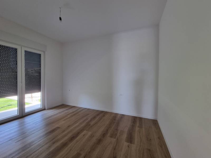 Ein leerer Raum mit Holzboden und Balkontüren in einer Vierzimmerwohnung.