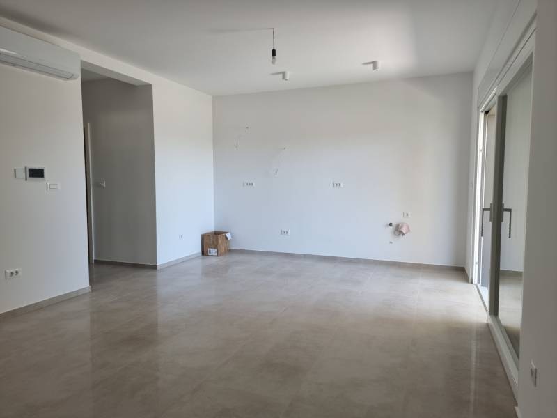 Geräumiges Wohnzimmer in einer 4-Zimmer-Wohnung mit Keramikboden und weißen Wänden.