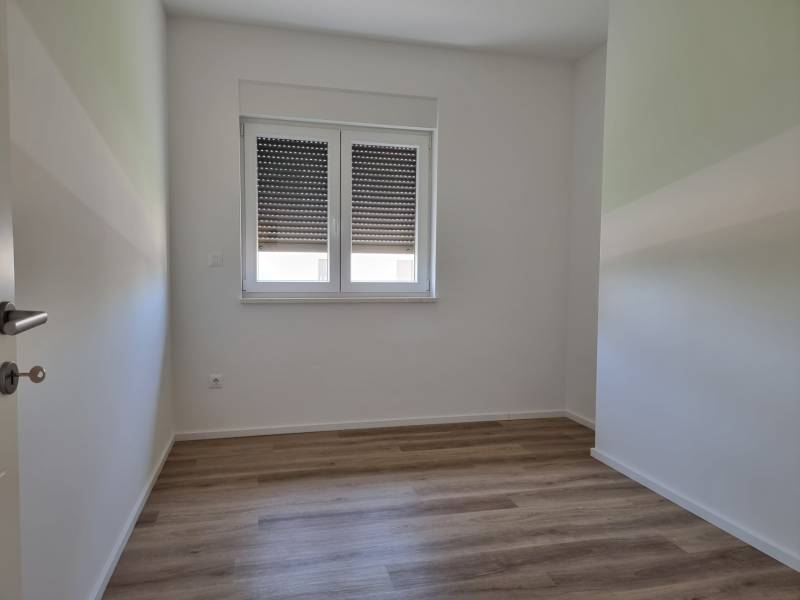 Ein Zimmer mit Holzboden und Fenster in einer 4-Zimmer-Wohnung.