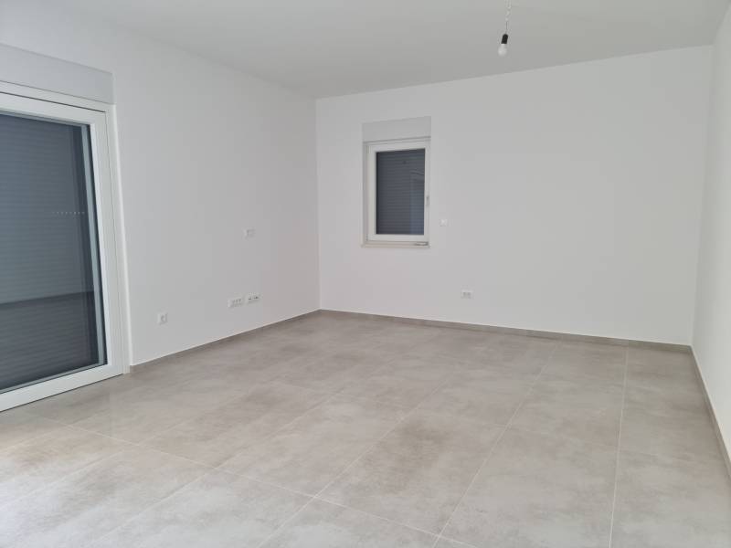 Leerer Raum mit hellen Wänden und Fliesen in einer 4-Zimmer-Wohnung.