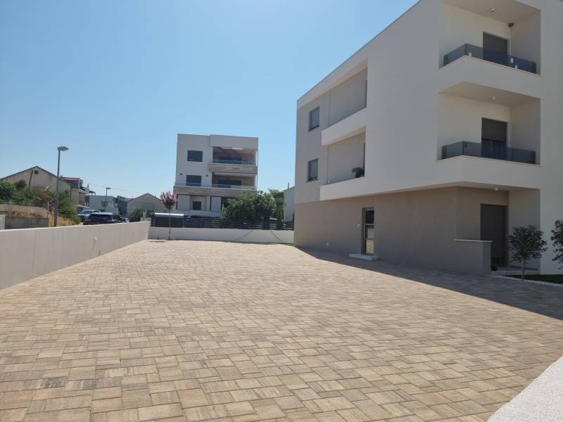In Vodice sind moderne Wohngebäude und eine gepflasterte Zufahrtsstraße sichtbar.