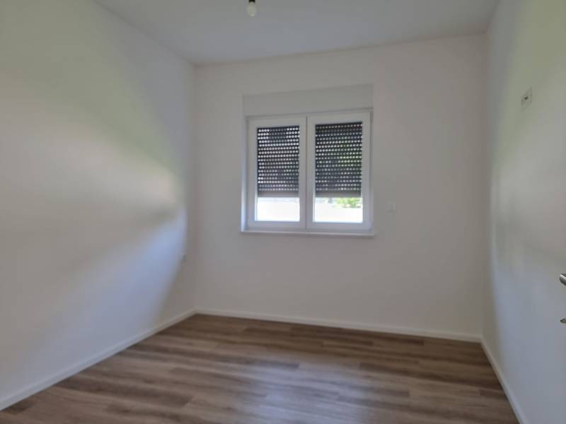 Leerer Raum mit Holzboden und Fenster, 3-Zimmer-Wohnung.