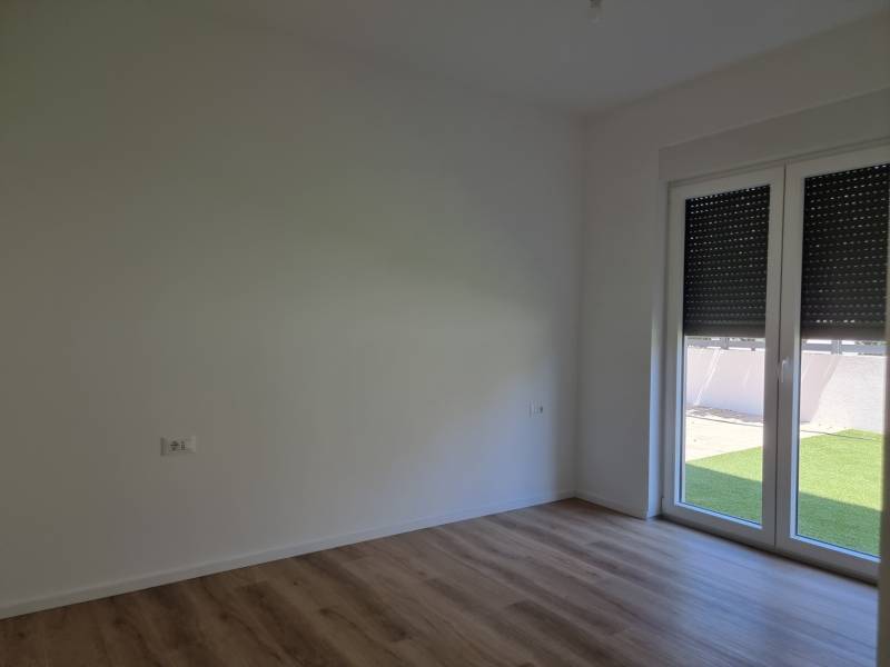 Ein leerer Raum in einer 3-Zimmer-Wohnung mit Holzboden und großem Fenster.