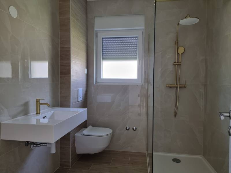 Badezimmer in einer 3-Zimmer-Wohnung mit Waschbecken, Toilette und Duschkabine.