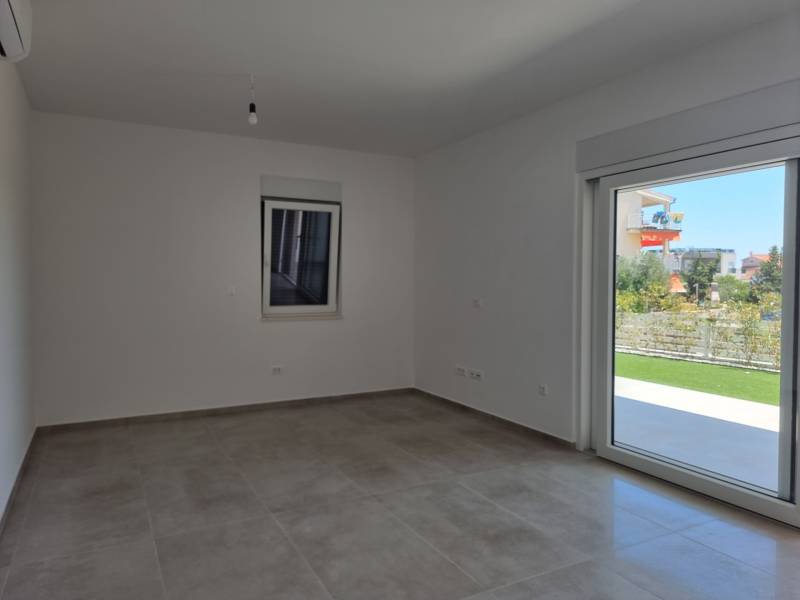 Helles Zimmer mit Keramikboden, Blick in den Garten und großem Fenster, 3-Zimmer-Wohnung.