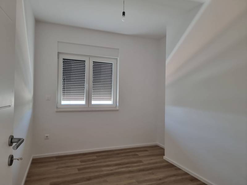 Innenraum einer 4-Zimmer-Wohnung mit Holzboden und heruntergelassenen Jalousien am Fenster.