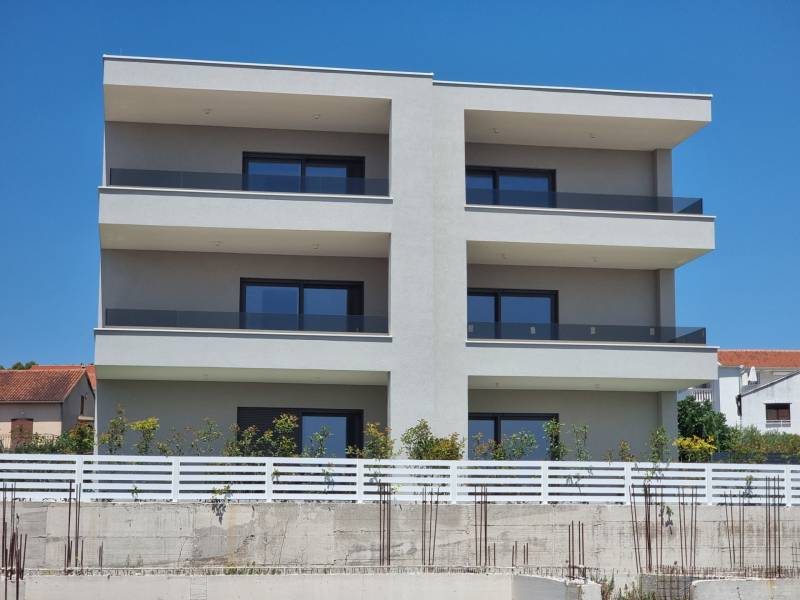Ein Wohnhaus in der Stadt Vodice mit drei Stockwerken und verglasten Balkonen.