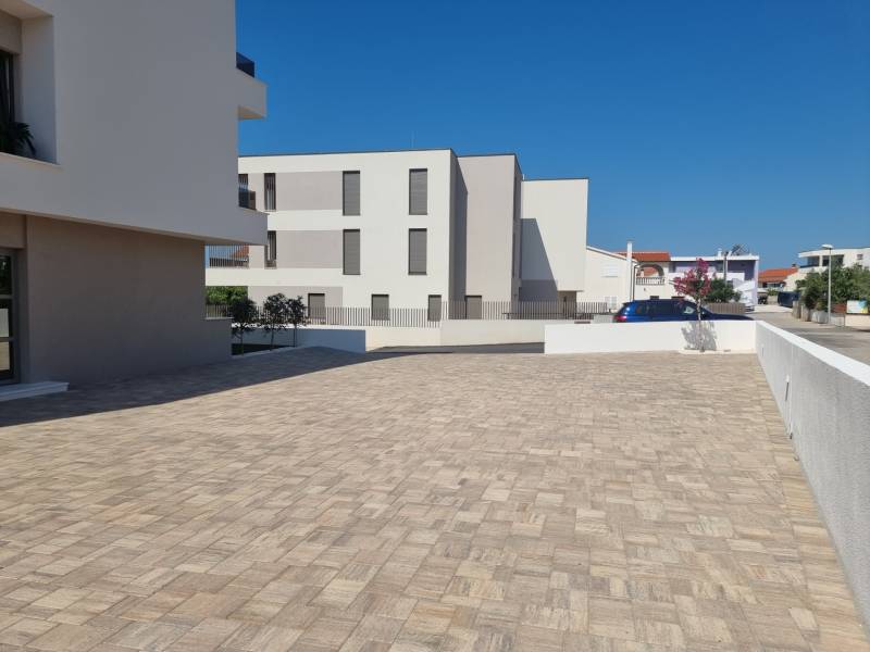 Parkplatz bei einer 4-Zimmer-Wohnung in der Stadt Vodice mit befestigter Oberfläche und klarer Architektur.
