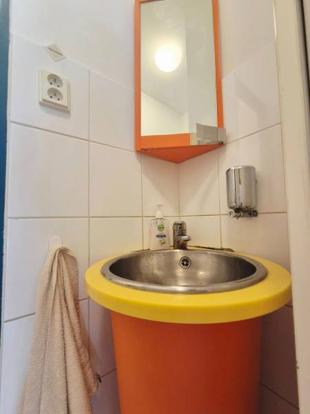 Ein orangefarbenes Waschbecken mit einem runden gelben Rand, ein Spiegel und ein Handtuchhalter.