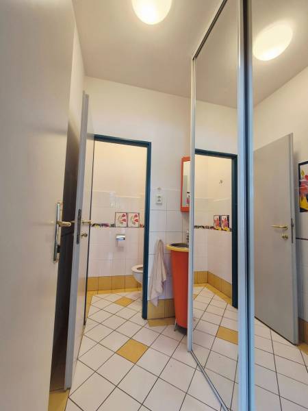 Toilette mit weißen und gelben Fliesen und einem orangefarbenen Waschbecken in Geschäftsräumen.