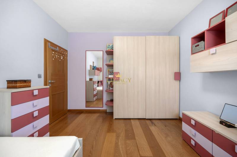 Kinderzimmer in einem Einfamilienhaus mit rosa und lila Kommoden, einem Spiegel und Holzboden.