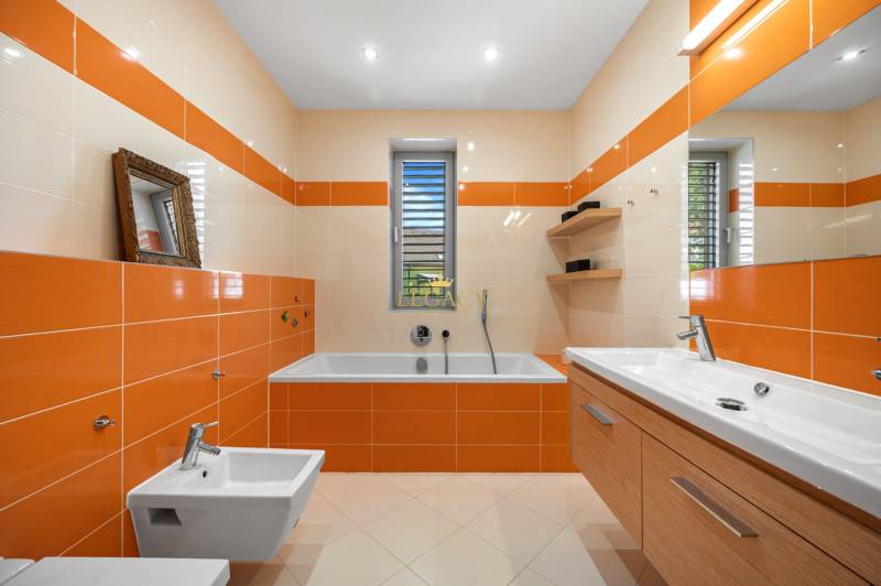 Ein Badezimmer in einem Einfamilienhaus mit orange-beigen Fliesen, einer Badewanne, einem Waschbecken und einem Bidet.