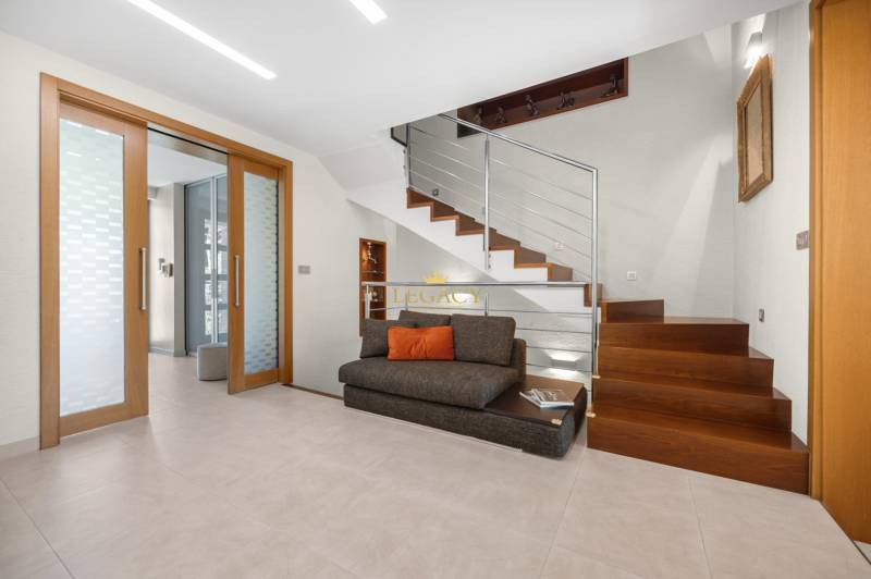 Einfamilienhaus mit Holztreppe, Glas und Sofa mit Kissen.
