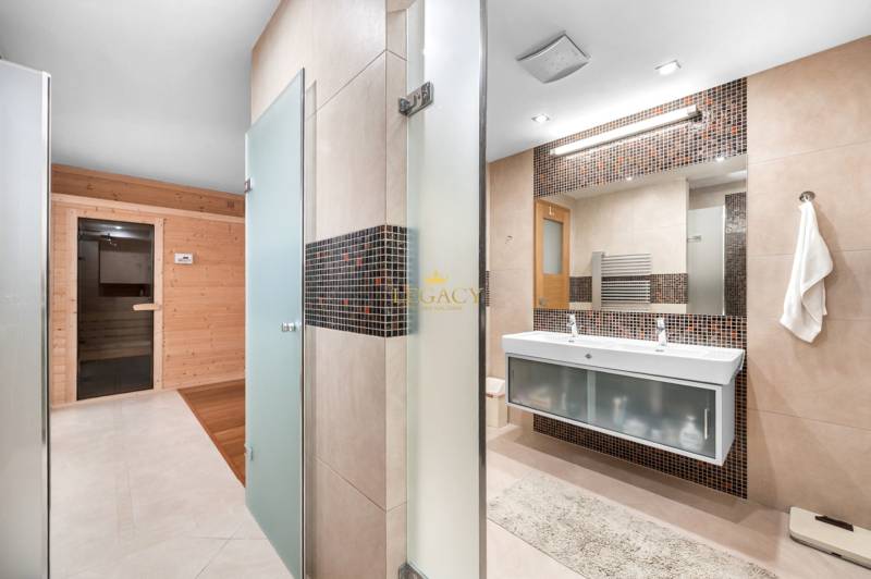 Badezimmer in einem Einfamilienhaus mit finnischer Sauna, zwei Waschbecken und Dusche.