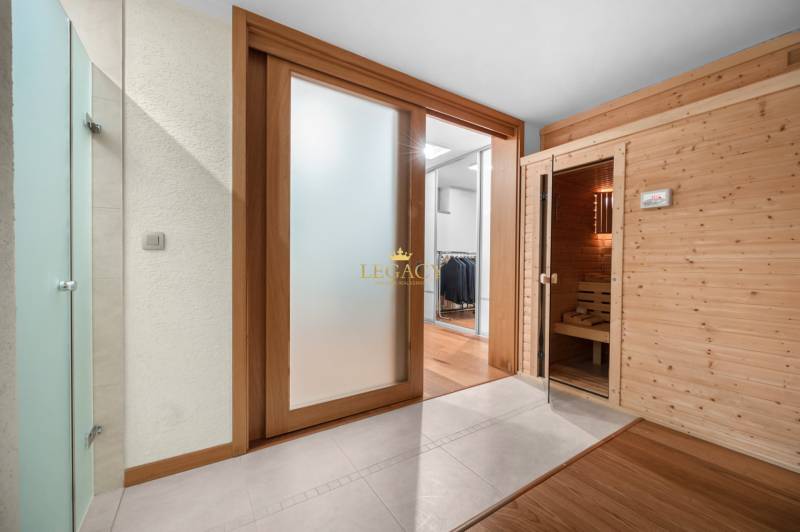 Innenraum eines Einfamilienhauses mit verglasten Schiebetüren und einer Holzsauna.