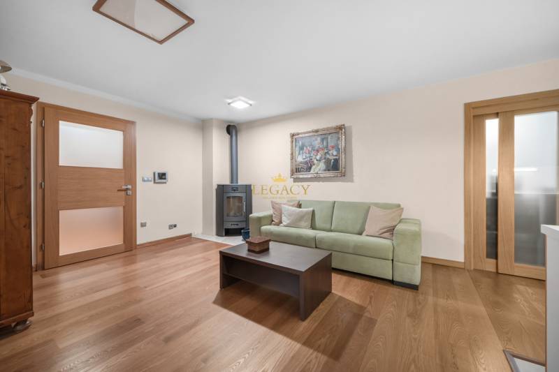 Wohnzimmer mit Holzboden, grüner Couch und Kachelkamin in einem Einfamilienhaus.