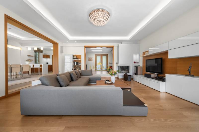 Wohnzimmer in einem Einfamilienhaus mit großem grauem Sofa und weißen Möbeln.