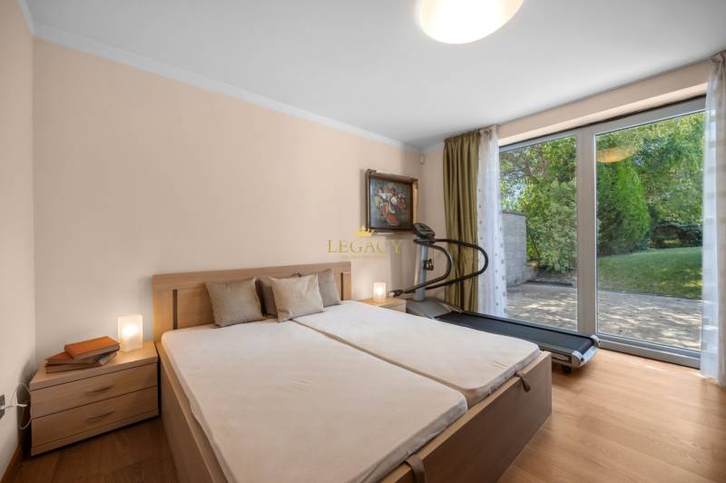 Schlafzimmer im Einfamilienhaus mit Ehebett, Laufband und Blick in den Garten.
