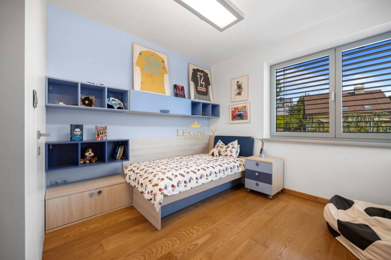 Kinderzimmer in einem Einfamilienhaus mit Bett, Regalen, Bildern und moderner Ausstattung.