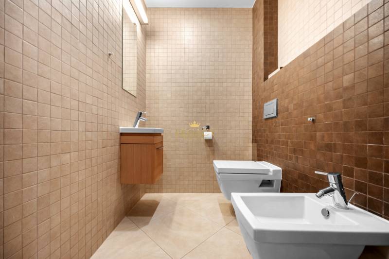 Badezimmer in einem Einfamilienhaus mit beigen Fliesen, Bidet und hängendem WC.