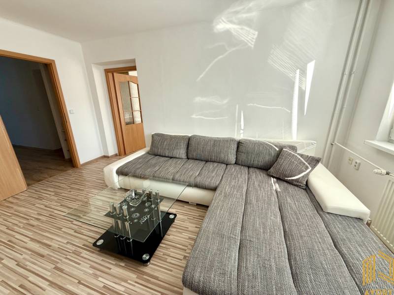 Helles Wohnzimmer mit Ecksofa und Glastisch in einer 2-Zimmer-Wohnung.