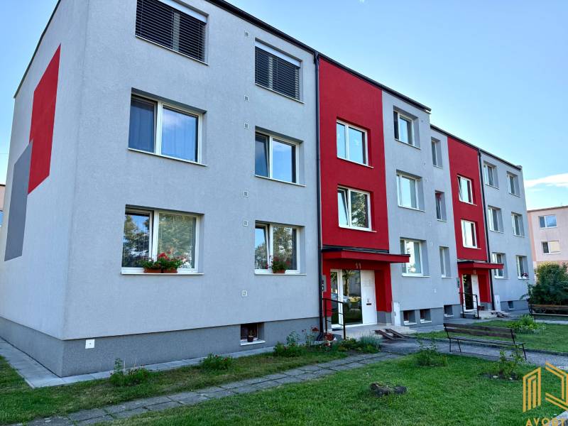 Ein Wohnblock auf dem Wohnsiedlung in Jablonica mit grauer Fassade und roten Elementen.