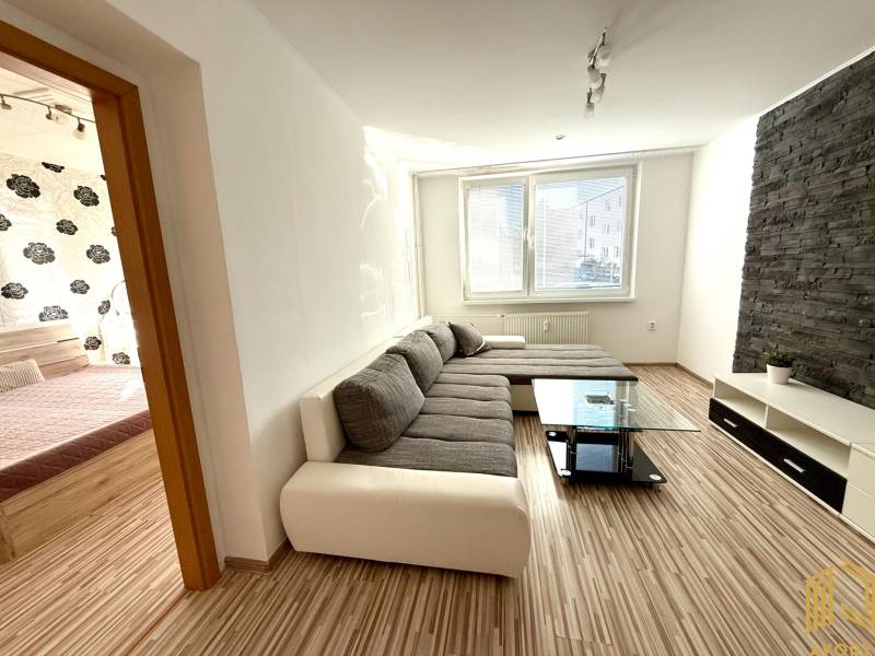 Wohnzimmer in einer 2-Zimmer-Wohnung mit moderner Sitzgelegenheit und dekorativer Wand.