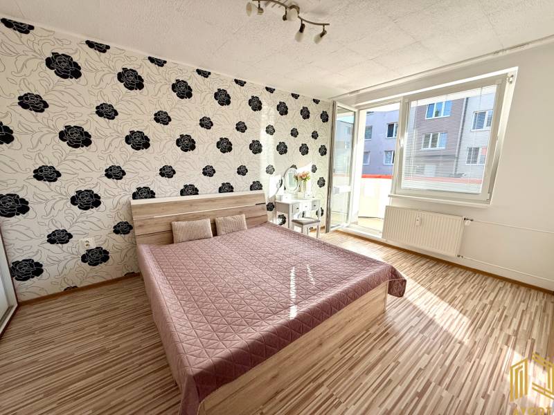 Schlafzimmer in einer 2-Zimmer-Wohnung mit gemusterten Tapeten und einem Doppelbett.