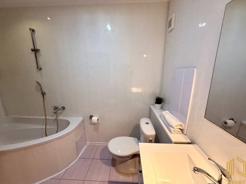 Badezimmer in einer 2-Zimmer-Wohnung mit Badewanne, Waschbecken und Toilette, helle Fliesen.